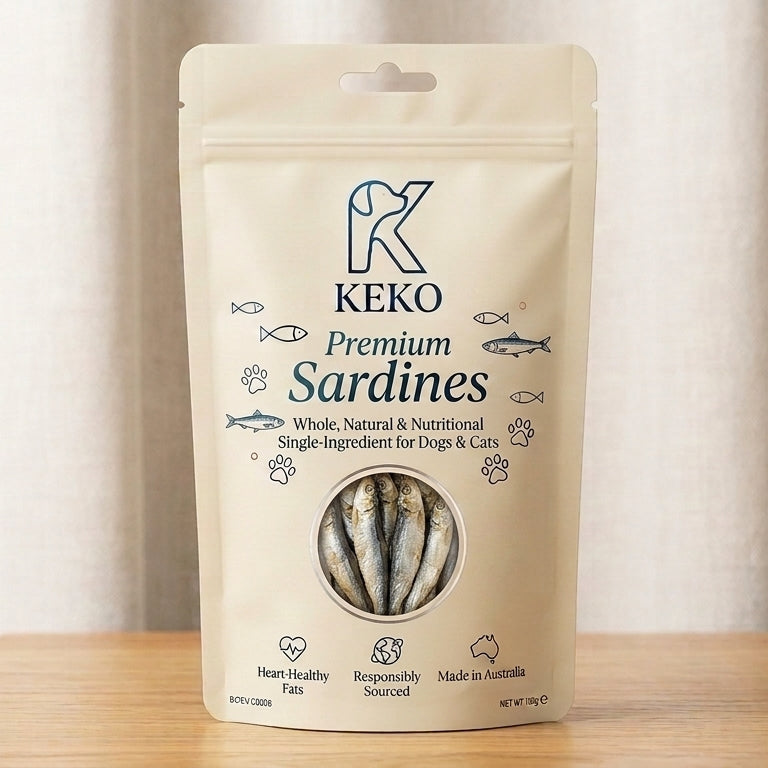 A stand-up pouch of KEKO Premium Sardines dog and cat treats, standing on a wooden surface against a soft beige curtain background.