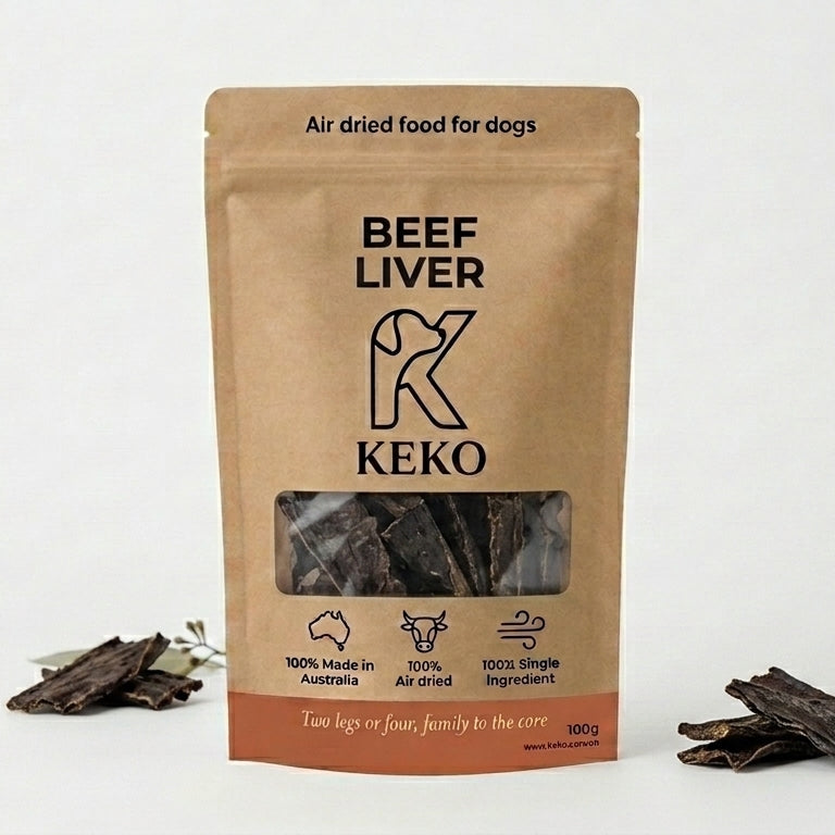 A stand-up kraft paper pouch of Keko Beef Liver air-dried food for dogs, displayed on a white background with a few pieces of the dog treats scattered at its base.